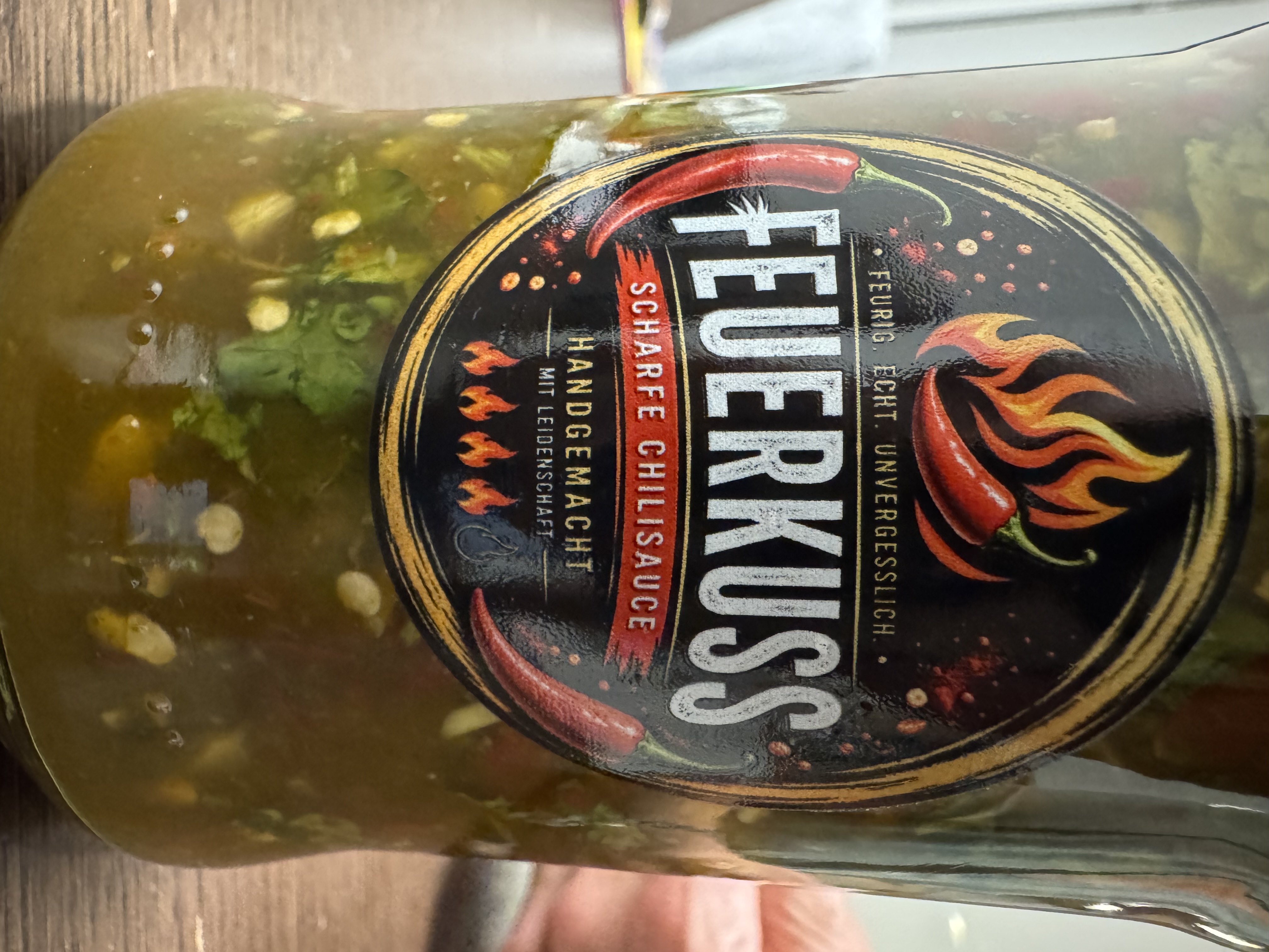 Rundes Etikett „Feuerkuss – scharfe Chilisauce" mit Chilischoten und Schärfeskala